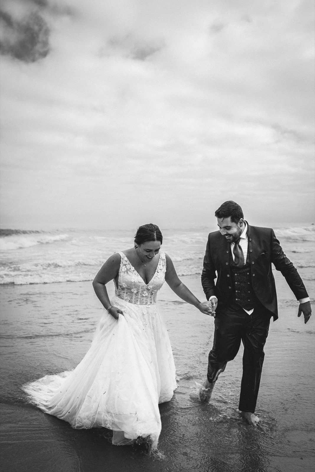 Novios paseando de la mano por la orilla del mar en una postboda en Galicia