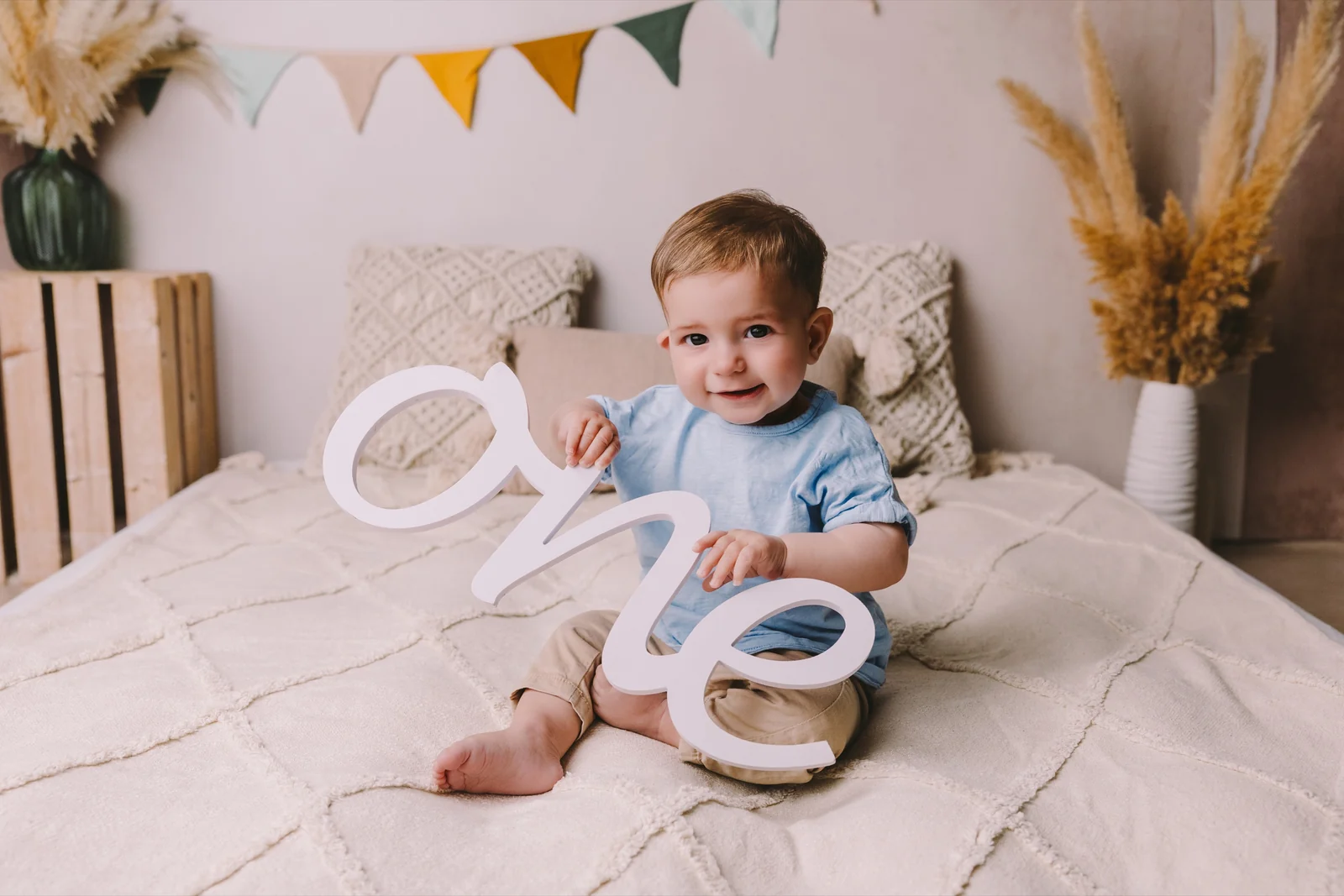 Sesión de cumpleaños en estudio en O Burgo, A Coruña — niño sobre una cama con banderines y el rótulo one
