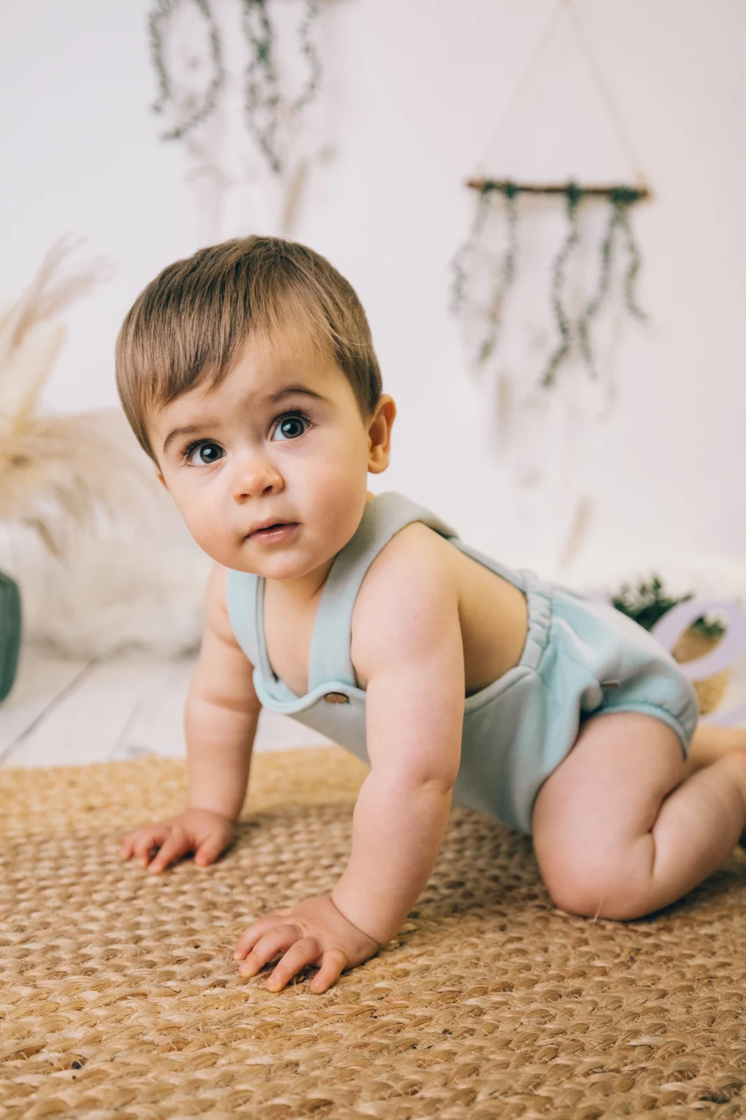 Bebé gateando sobre alfombra de yute en decorado boho