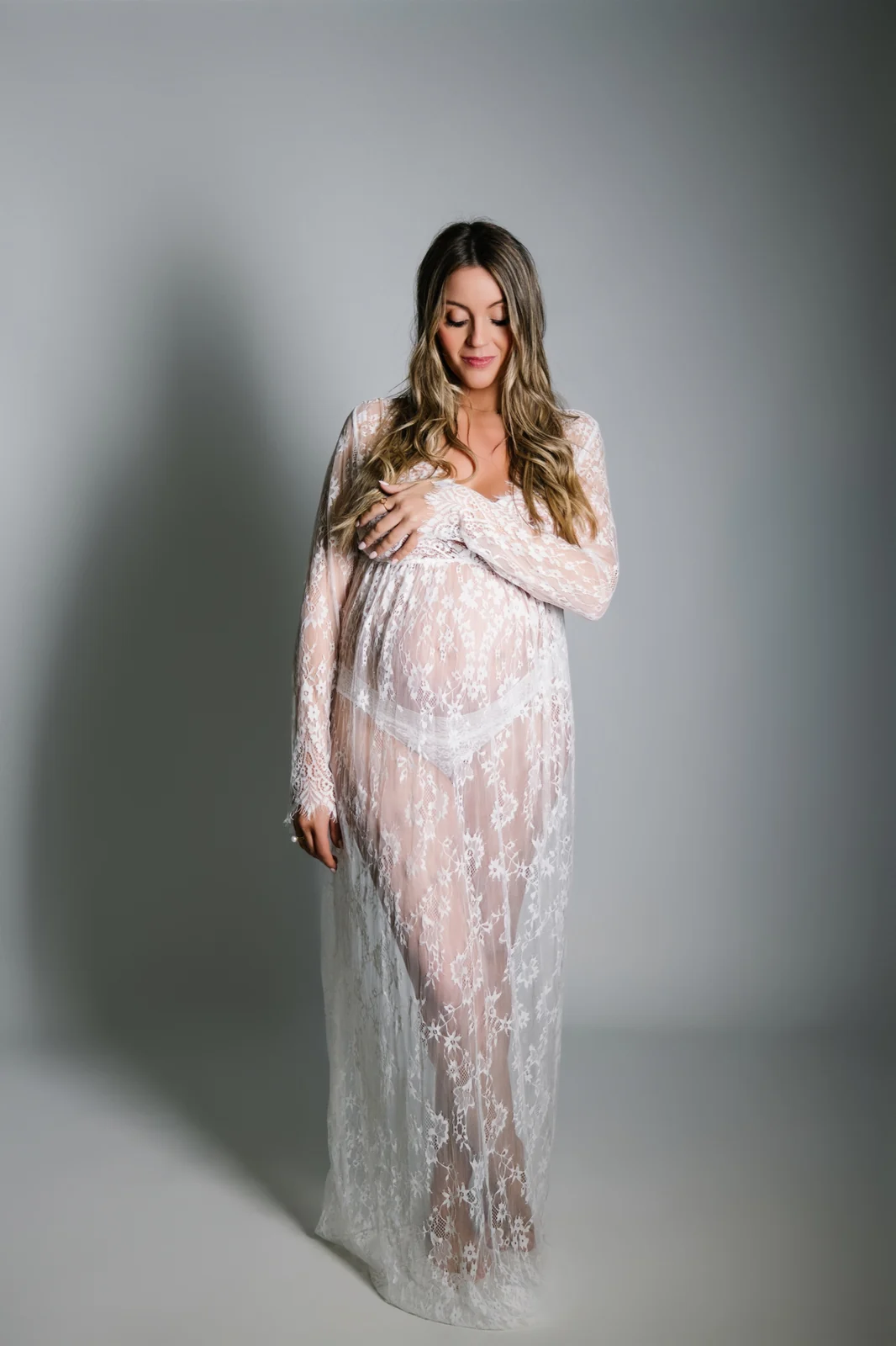 Embarazada con vestido blanco de encaje en estudio