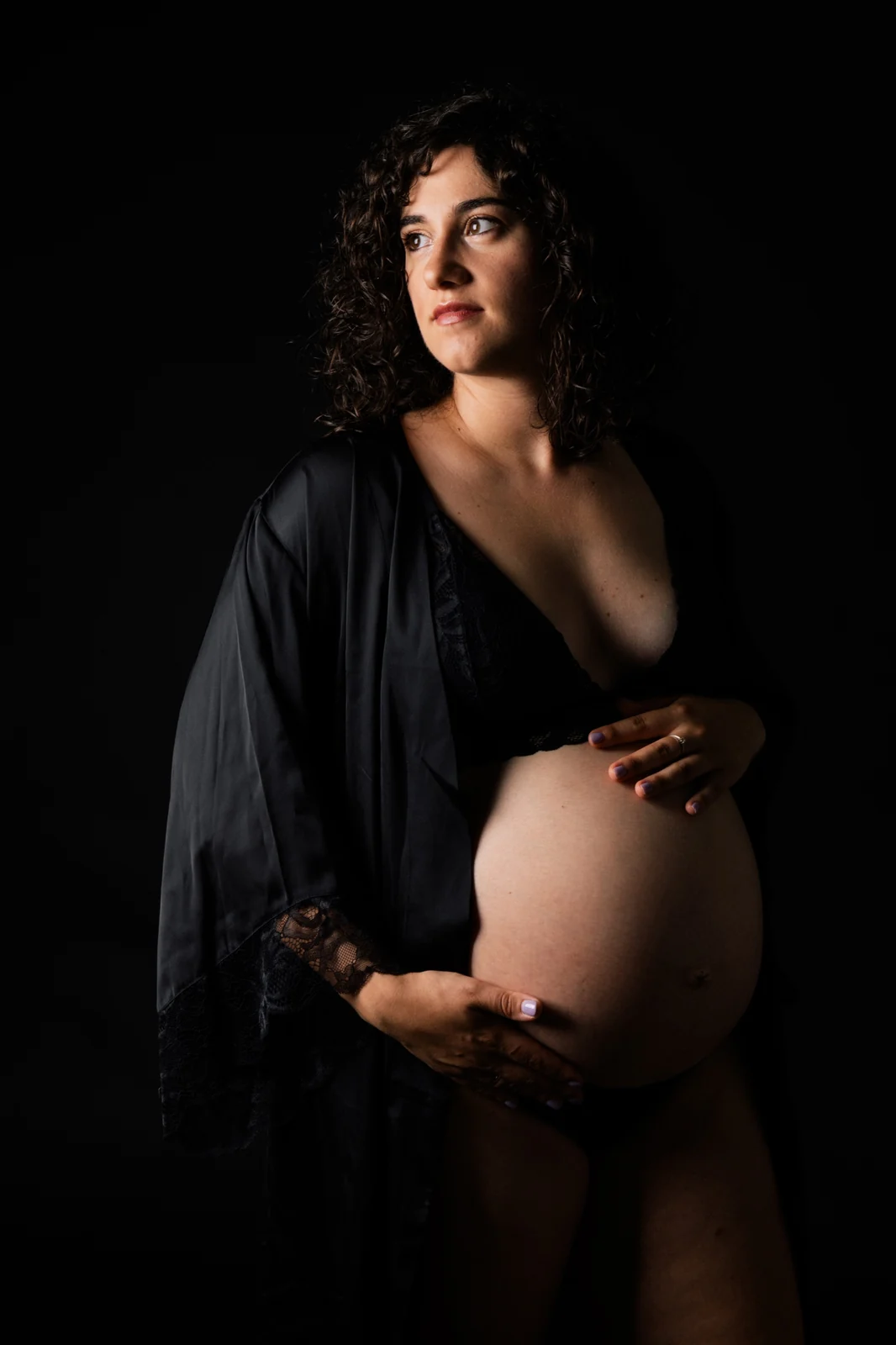 Retrato de embarazada con bata negra, fondo negro