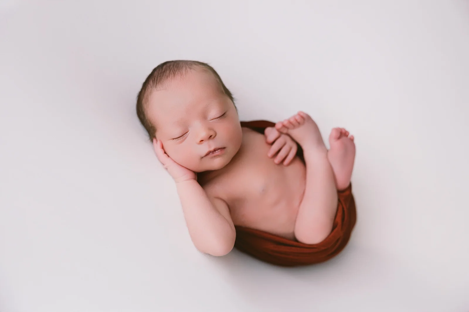 Recién nacido dormido con las manos bajo la mejilla, sesión newborn en estudio en O Burgo, A Coruña
