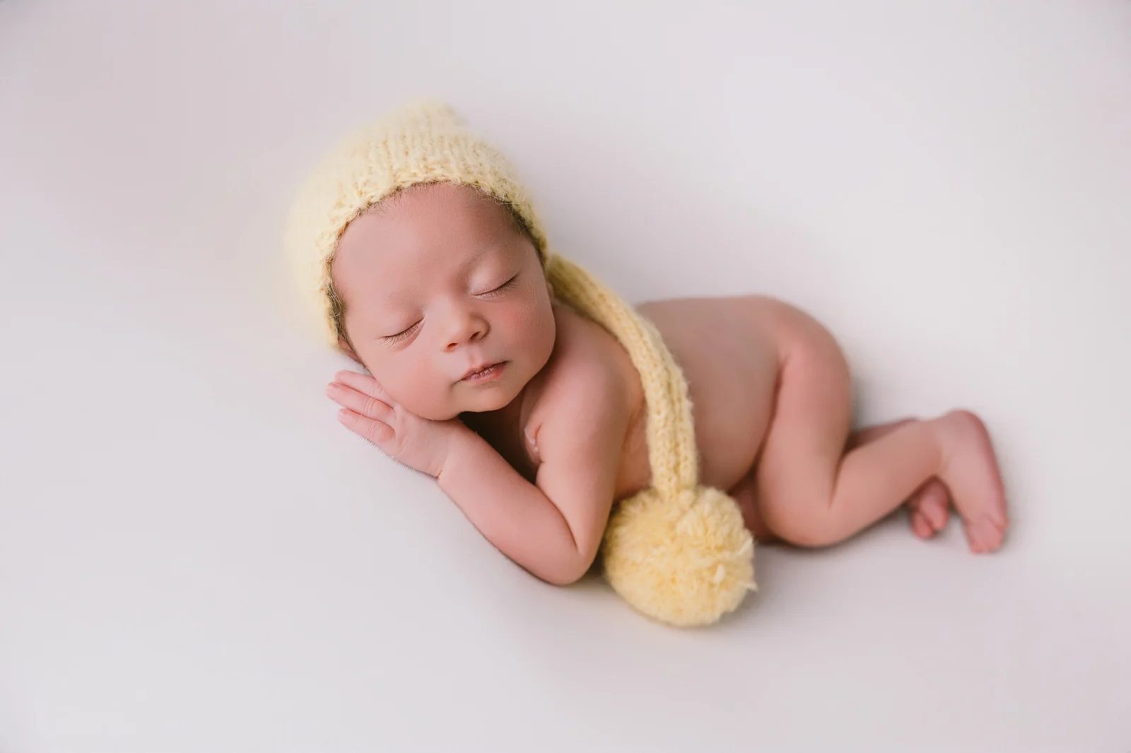 Bebé recién nacido dormido con gorrito de lana, sesión newborn en estudio en O Burgo, A Coruña